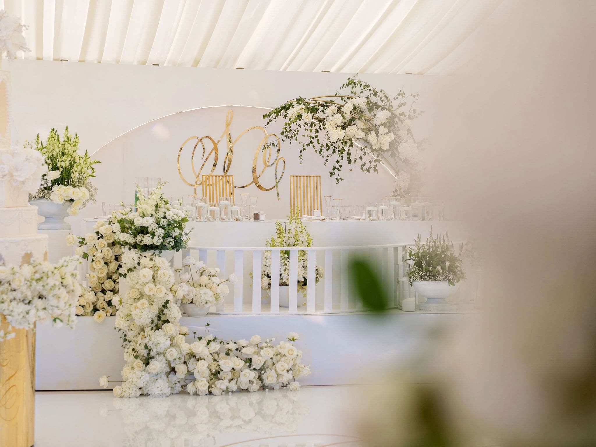 White roses and a gold monogram behind the couple's reception table