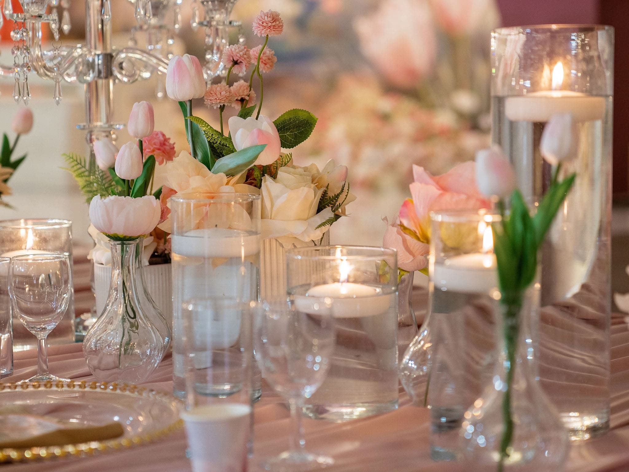 Peach flowers and candles beside personalised table settings